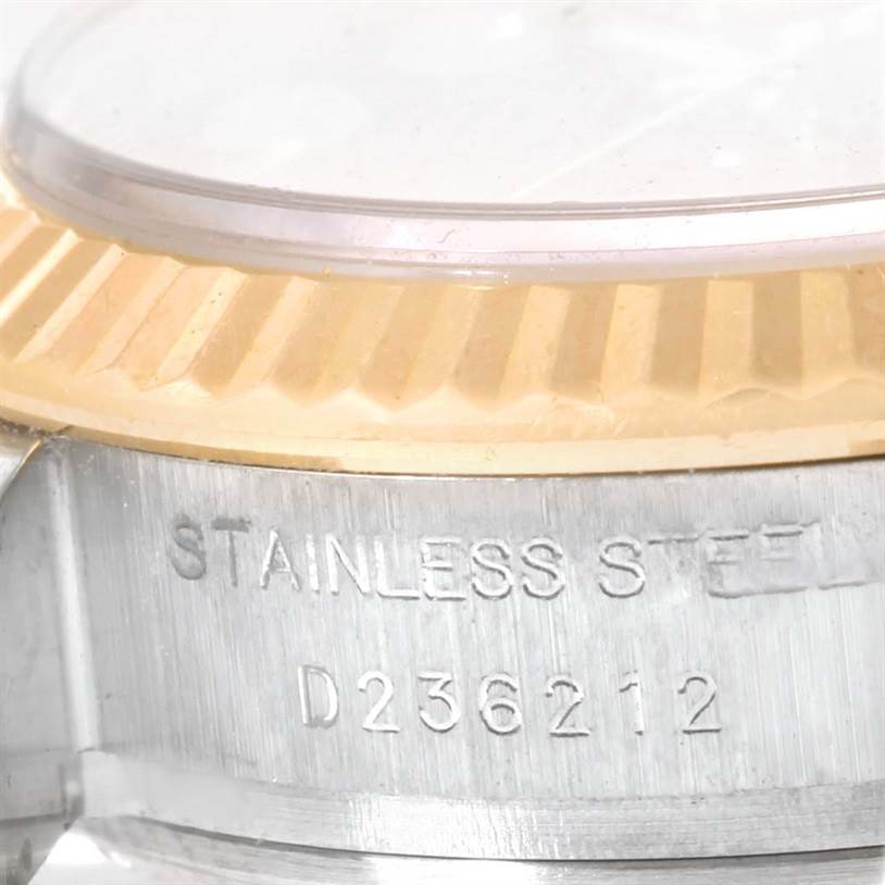 This image shows a close-up of the side of a Rolex Datejust 179173 Women's Steel and Gold (two tone) Black Dial 179173 Women's Steel and Gold (two tone) Black Dial watch, displaying parts of the bezel and the engraved case.