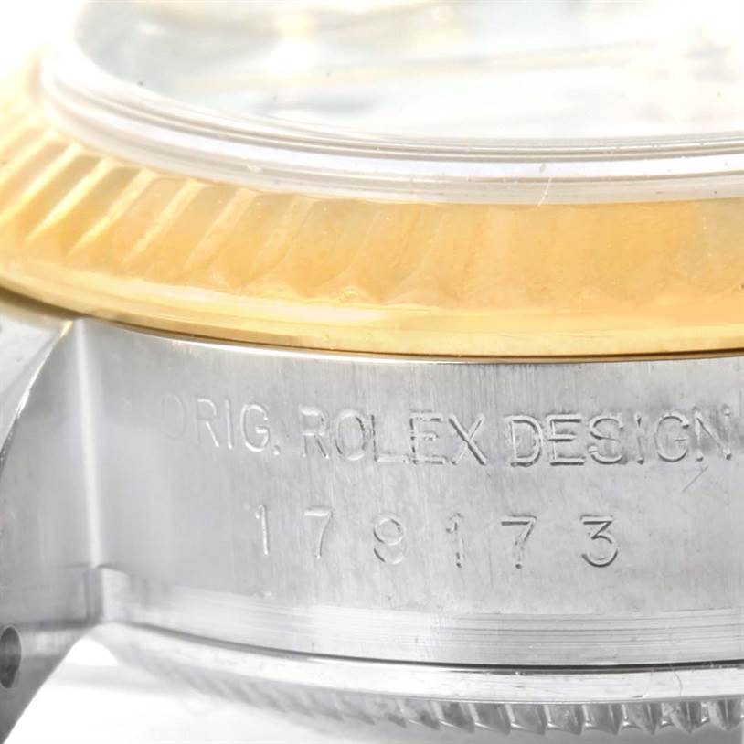 This close-up image shows the serial number and fluted bezel of the Rolex Datejust 179173 Women's Steel and Gold (two tone) Black Dial 179173 Women's Steel and Gold (two tone) Black Dial watch with part of the case visible.