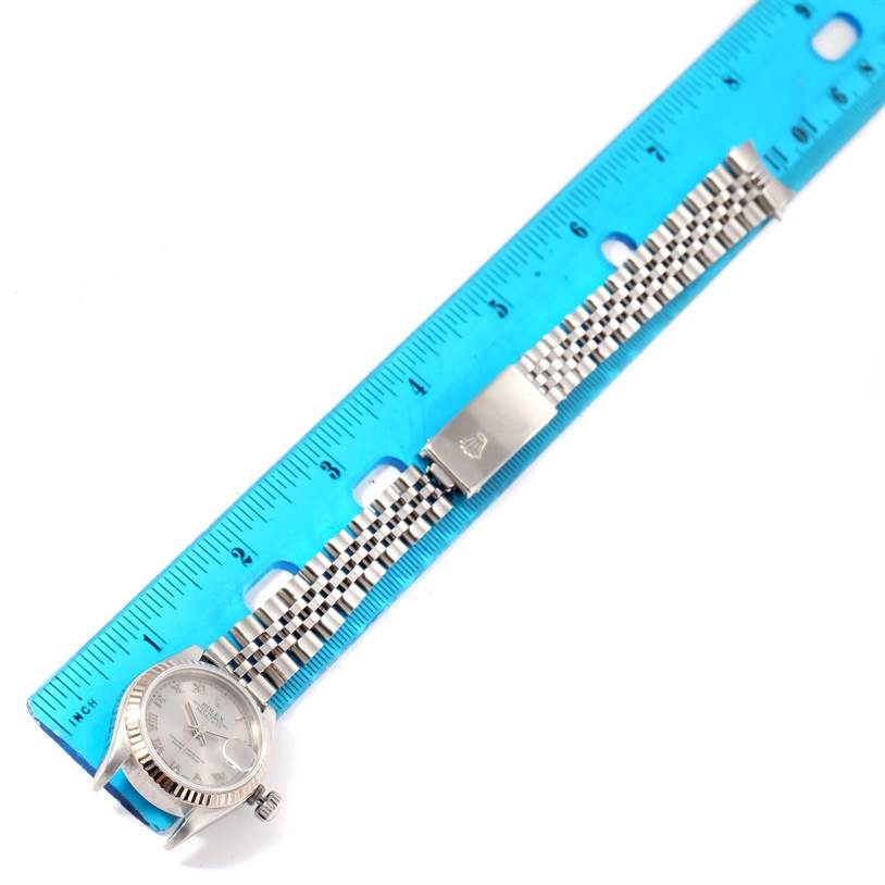 The image shows a Rolex Datejust 79174 Women
s Stainless Steel Silver Dial 79174 Women
s Stainless Steel Silver Dial watch laid flat next to a ruler, highlighting the watch face and metal bracelet.