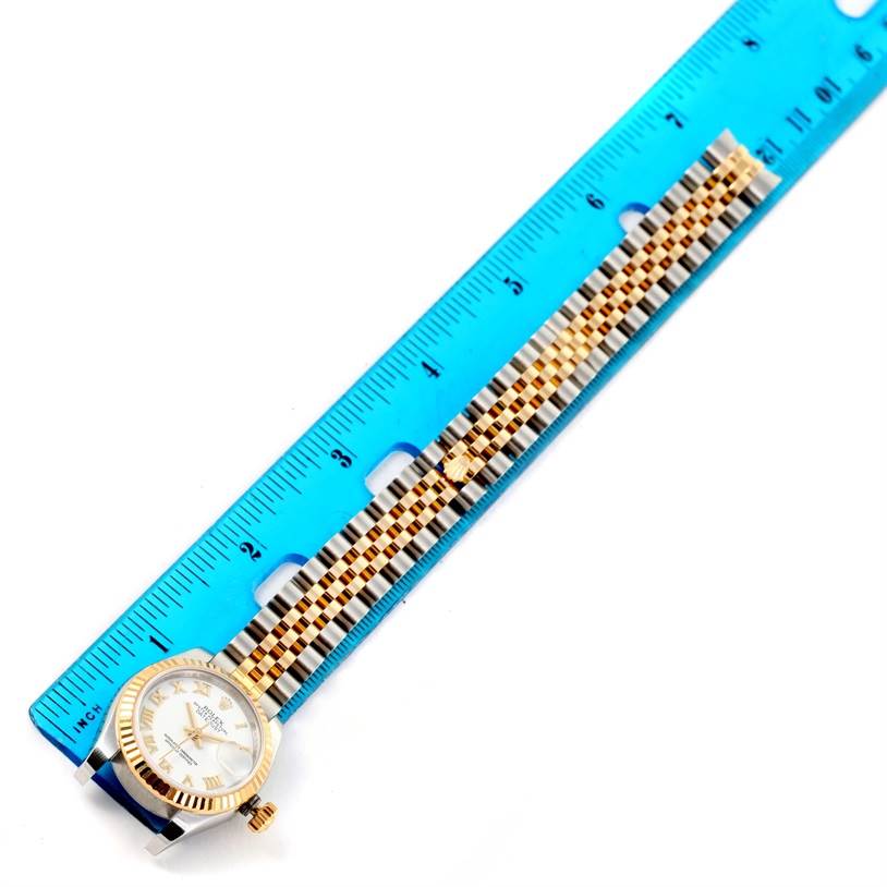 The Rolex Datejust 179173 Women's Steel and Gold (two tone) White Dial 179173 Women's Steel and Gold (two tone) White Dial watch is shown from a top-down angle next to a blue ruler, highlighting its face and bracelet.