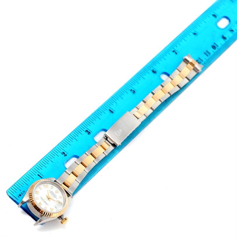 The image shows a top-down view of a Rolex Datejust 79173 Women
s Stainless Steel White Dial 79173 Women
s Stainless Steel White Dial watch placed next to a blue measuring ruler.