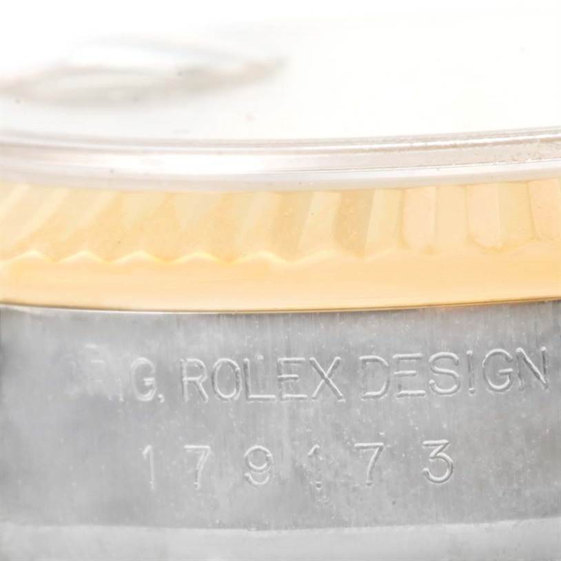 This close-up image shows the side of a Rolex Datejust 179173 Women's Steel and Gold (two tone) Silver Dial 179173 Women's Steel and Gold (two tone) Silver Dial watch with the model number 179173 and part of the fluted bezel.