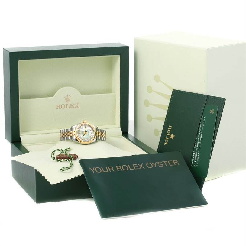 The image shows a Rolex Datejust 179173 Women's Steel and Gold (two tone) Mother of Pearl Dial 179173 Women's Steel and Gold (two tone) Mother of Pearl Dial watch in an open green box with accompanying accessories, including manuals and a tag.