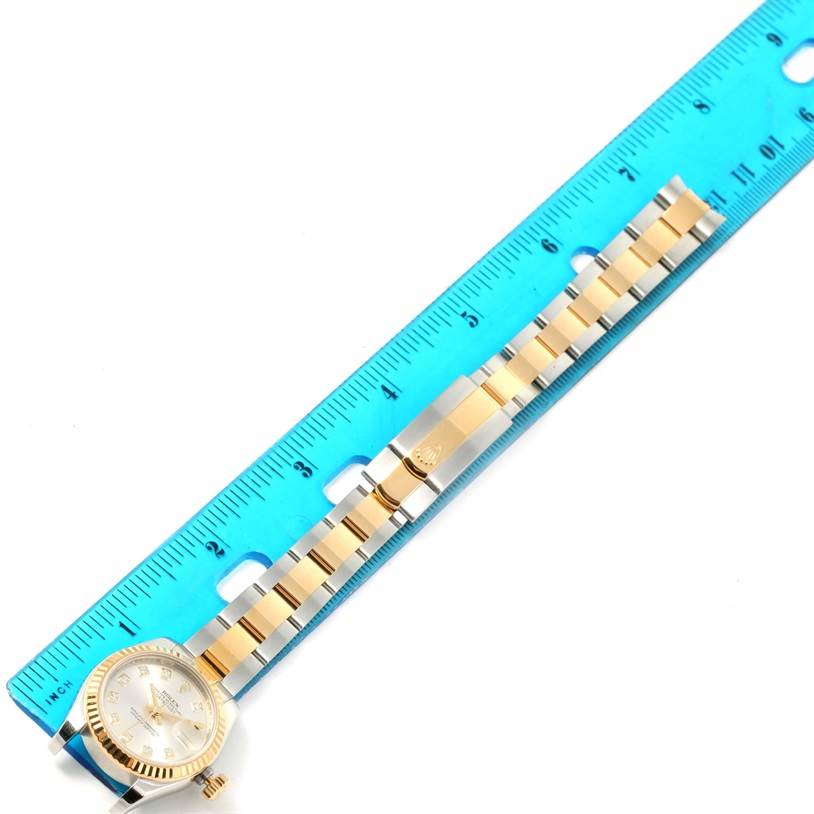 The image shows a Rolex Datejust 179173SDO Women's Steel and Gold (two tone) Silver Dial 179173SDO Women's Steel and Gold (two tone) Silver Dial watch from a top-down angle, highlighting its face, bezel, and bracelet next to a blue ruler for scale.
