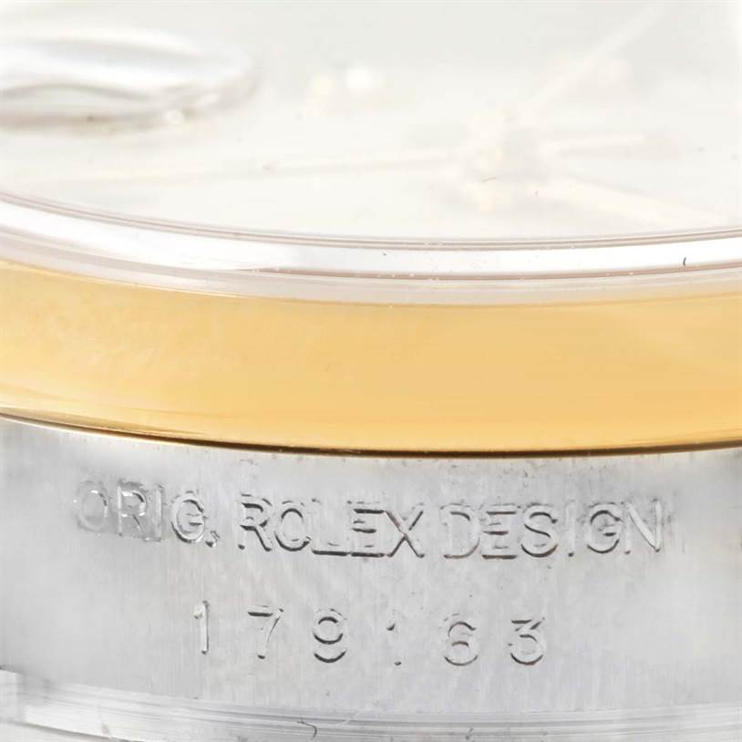 This image shows a close-up of the side of a Rolex Datejust 179163 Women's Steel and Gold (two tone) Silver Dial 179163 Women's Steel and Gold (two tone) Silver Dial watch, highlighting an engraved inscription and the edge of the watch face.