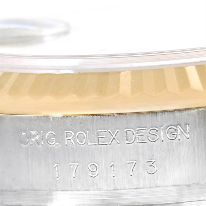 The image shows a close-up of the side engraving and part of the bezel of a Rolex Datejust 179173 Women's Steel and Gold (two tone) Silver Dial 179173 Women's Steel and Gold (two tone) Silver Dial watch.