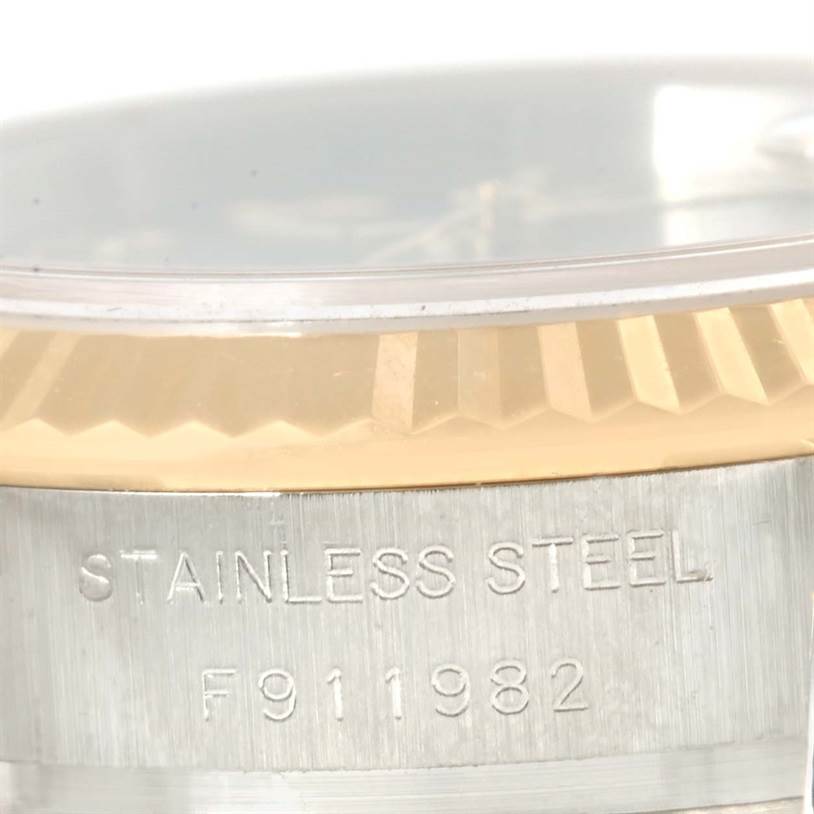 This image shows a close-up of the bezel and side case of a Rolex Datejust 179173 Women's Steel and Gold (two tone) Silver Dial 179173 Women's Steel and Gold (two tone) Silver Dial watch, highlighting the stainless steel mark and serial number.