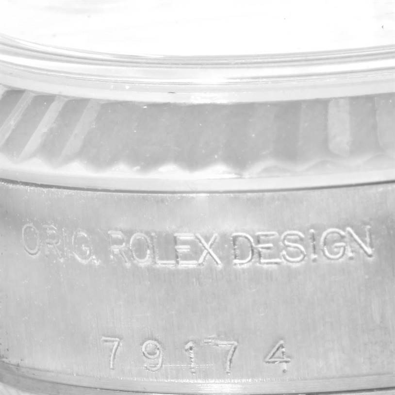 This image shows a close-up of the side of a Rolex Datejust 79174 Women's Stainless Steel Grey Dial 79174 Women's Stainless Steel Grey Dial watch, highlighting the engraved "ORIG. ROLEX DESIGN" and the model number.