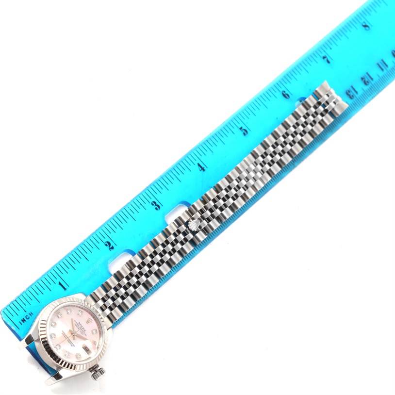 The image shows the Rolex Datejust 179174 Women's Stainless Steel Mother of Pearl Dial 179174 Women's Stainless Steel Mother of Pearl Dial watch face and part of its metal bracelet, positioned next to a ruler.