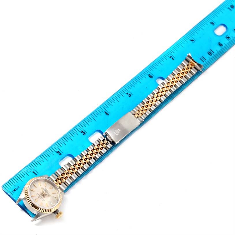 This image shows a Rolex Datejust 69173 Women
s Stainless Steel Silver Dial 69173 Women
s Stainless Steel Silver Dial watch laid flat alongside a blue ruler, displaying its dial, case, and Jubilee bracelet.