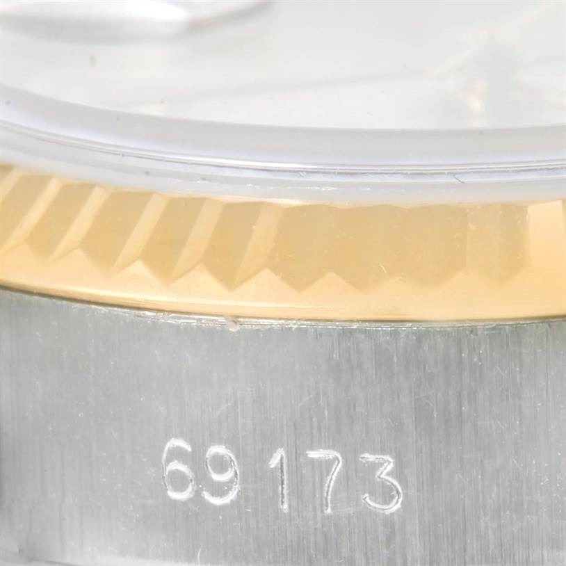 The image shows a close-up of a Rolex Datejust 69173 Women
s Stainless Steel Silver Dial 69173 Women
s Stainless Steel Silver Dial model watch, highlighting the bezel, crystal, and part of the case with the serial number.