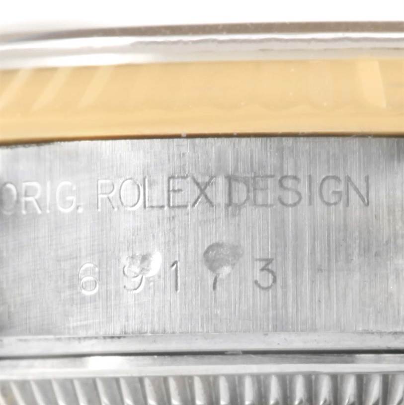 This is a macro shot of the serial number and "ORIG. ROLEX DESIGN" engraving on the casing of a Rolex Datejust 69173 Women
s Stainless Steel Champagne Dial 69173 Women
s Stainless Steel Champagne Dial watch.
