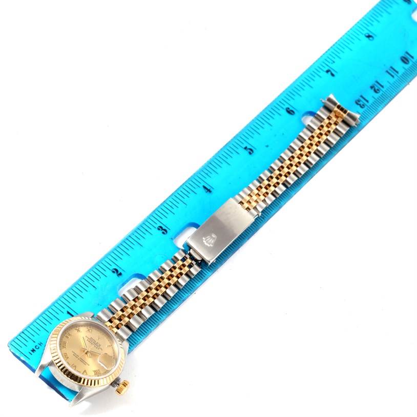 The image shows a Rolex Datejust 79173 Women
s Stainless Steel Champagne Dial 79173 Women
s Stainless Steel Champagne Dial watch laid flat next to a ruler, displaying its face, band, and clasp.