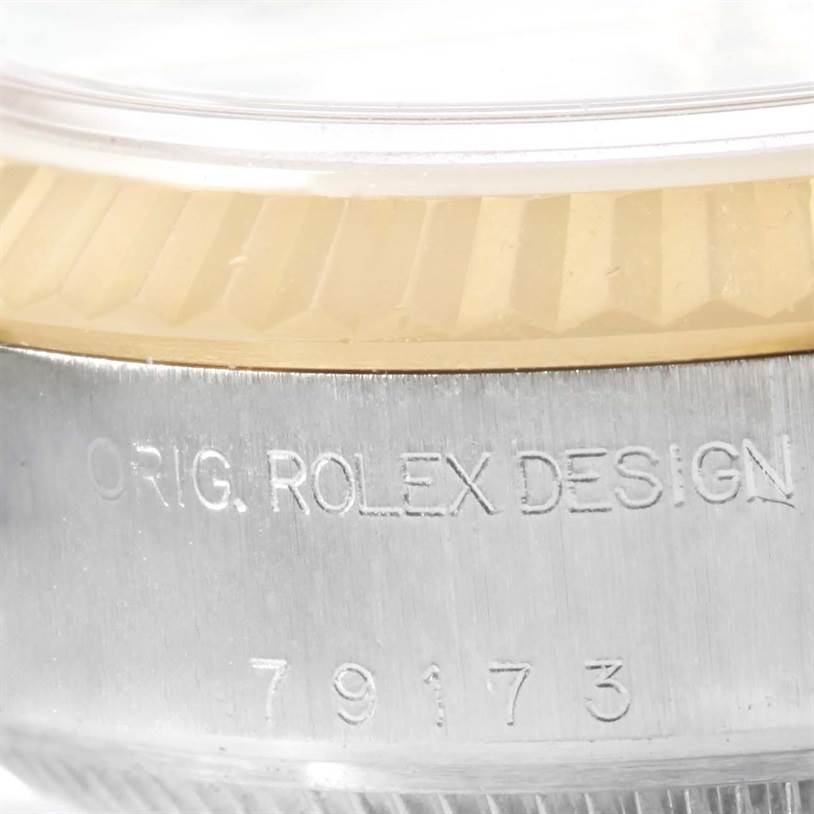 This close-up image shows the side of a Rolex Datejust 79173 Women's Stainless Steel Beige Dial 79173 Women's Stainless Steel Beige Dial watch, showcasing the bezel and engraved serial number.