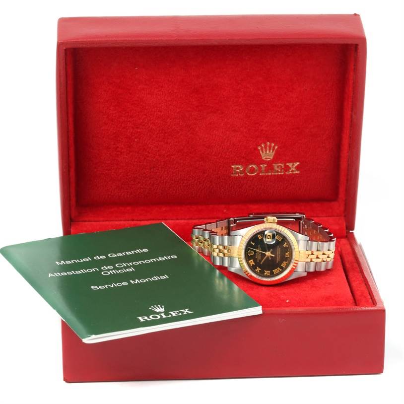 The Rolex Datejust 69173 Women
s Stainless Steel Black Dial 69173 Women
s Stainless Steel Black Dial watch is shown in its opened red box with a manual beside it.