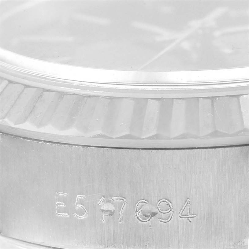 This is a close-up angle of the case and bezel of a Rolex Datejust 69174 Women's Stainless Steel Black Dial 69174 Women's Stainless Steel Black Dial watch, featuring engraved serial numbers.