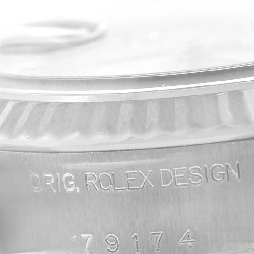 This close-up image of a Rolex Datejust 79174 Women's Stainless Steel Mother of Pearl Dial 79174 Women's Stainless Steel Mother of Pearl Dial watch shows the detailed engraving with the text "ORIG. ROLEX DESIGN" and part of the model number.