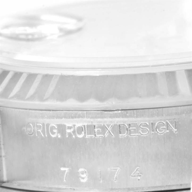 This image shows a close-up of the side of a Rolex Datejust 79174 Women
s Stainless Steel Silver Dial 79174 Women
s Stainless Steel Silver Dial watch, highlighting the "ORIG. ROLEX DESIGN" engraving and model number 79174.