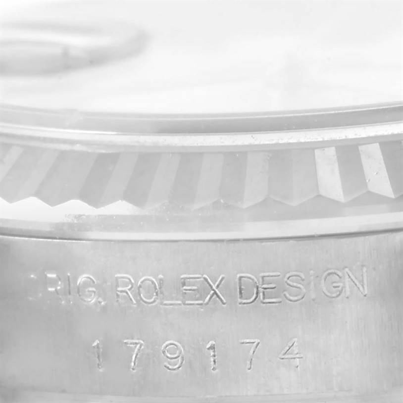 This close-up image of a Rolex Datejust 179174 Women's Stainless Steel Mother of Pearl Dial 179174 Women's Stainless Steel Mother of Pearl Dial watch shows the fluted bezel and the engraved serial number on the case.