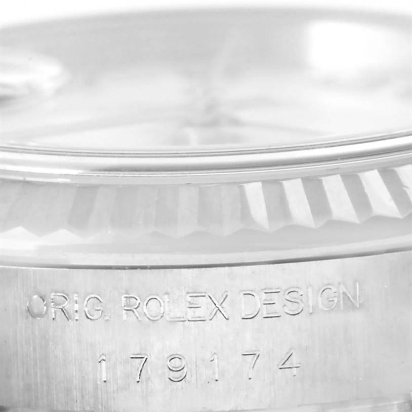 This close-up image of a Rolex Datejust 179174 Women
s Stainless Steel White Dial 179174 Women
s Stainless Steel White Dial watch shows the case engraved with "ORIG. ROLEX DESIGN" and model number "179174".