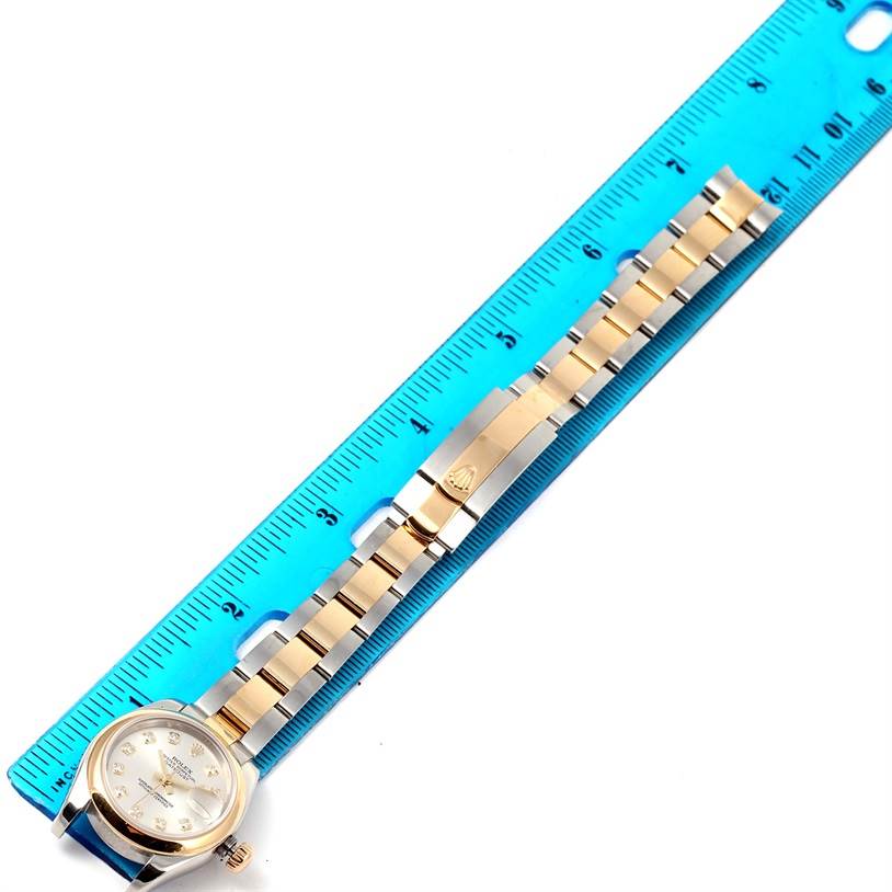 The Rolex Datejust 179163 Women's Steel and Gold (two tone) Silver Dial 179163 Women's Steel and Gold (two tone) Silver Dial watch is shown from a top-down angle, displaying its full gold and silver bracelet alongside a blue ruler for size reference.