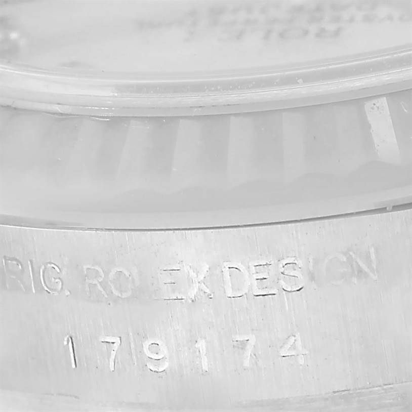 The image shows a close-up of the side of a Rolex Datejust 179174 Women's Stainless Steel Mother of Pearl Dial 179174 Women's Stainless Steel Mother of Pearl Dial watch with the engraved model number and part of the fluted bezel.