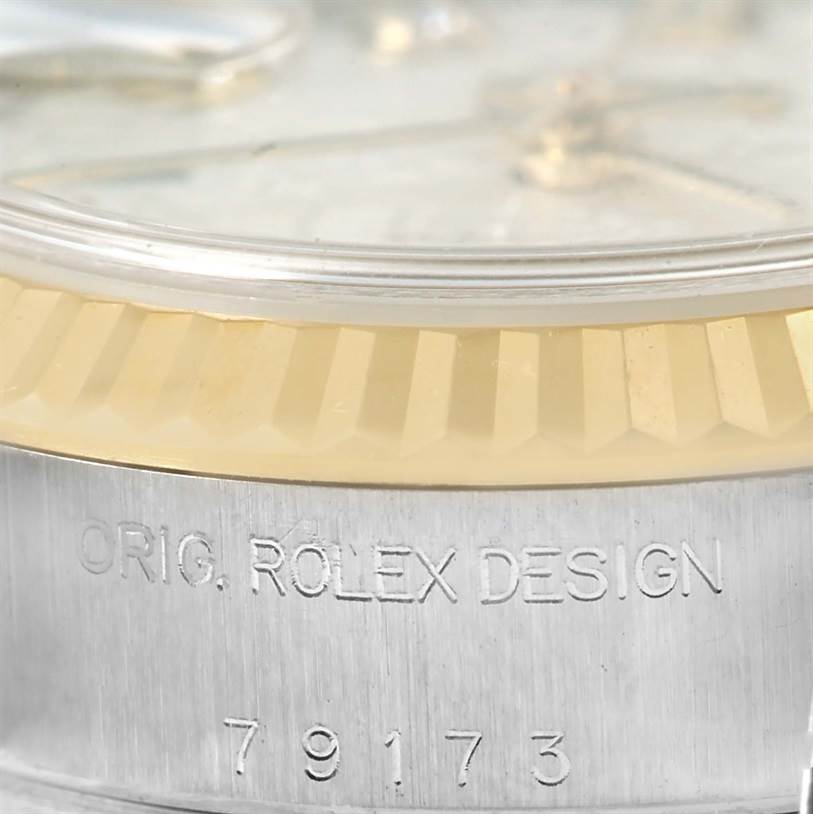 The image shows a close-up of the Rolex Datejust 79173 Women's Stainless Steel Silver Dial 79173 Women's Stainless Steel Silver Dial watch's case, highlighting the fluted bezel and engraved serial number.