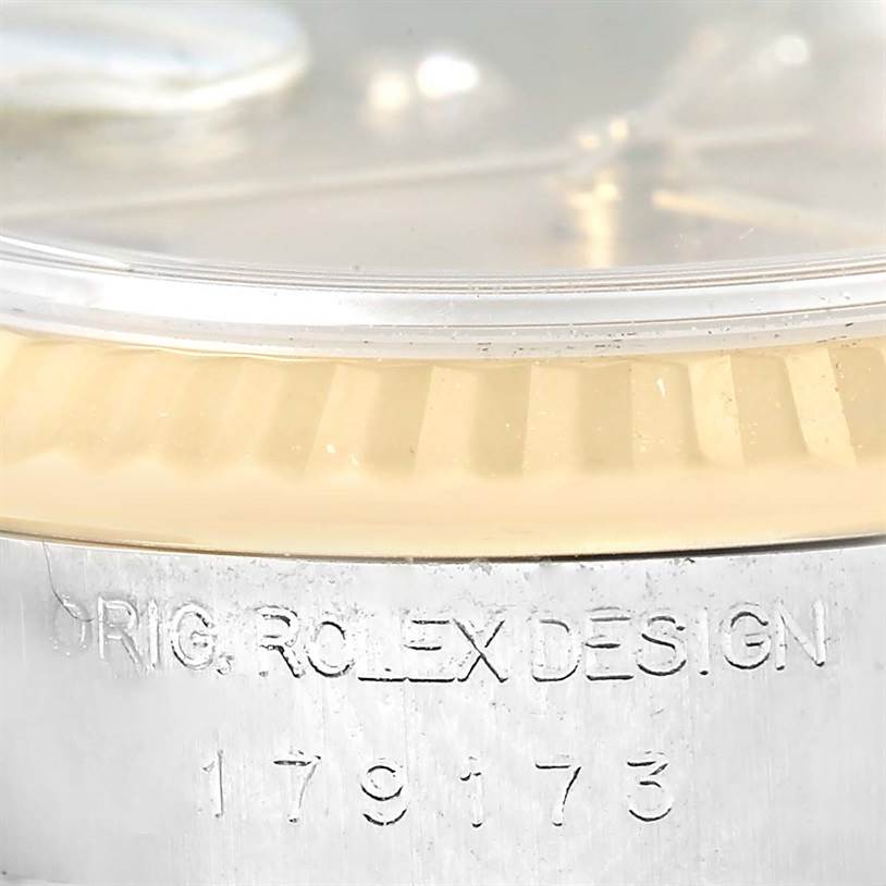 This image shows a close-up of the side of a Rolex Datejust 179173 Women's Steel and Gold (two tone) Champagne Dial 179173 Women's Steel and Gold (two tone) Champagne Dial watch, displaying the model number and "ORIG. ROLEX DESIGN" engraving.