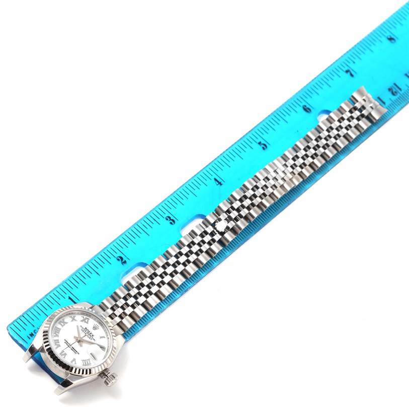 The Rolex Datejust 179174 Women's Stainless Steel White Dial 179174 Women's Stainless Steel White Dial watch is shown from above, highlighting the face and the full length of the wristband placed next to a ruler.