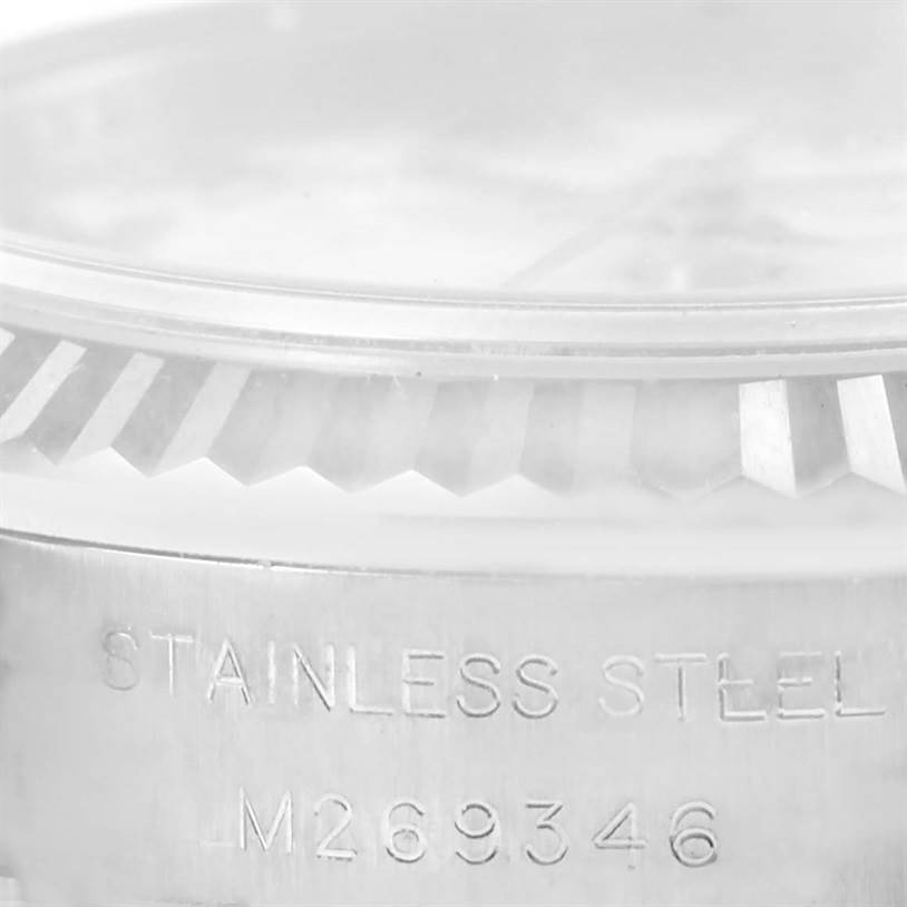 The image shows a close-up of the side of a Rolex Datejust 179174 Women's Stainless Steel White Dial 179174 Women's Stainless Steel White Dial watch, highlighting the fluted bezel and stainless steel casing with the serial number.