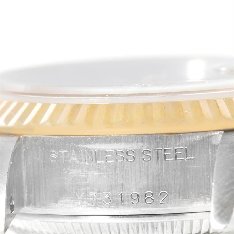 This image shows a close-up side view of a Rolex Datejust 79173 Women's Steel and Gold (two tone) Mother of Pearl Dial 79173 Women's Steel and Gold (two tone) Mother of Pearl Dial watch, highlighting the fluted bezel and the "STAINLESS STEEL" engraving with a serial number.