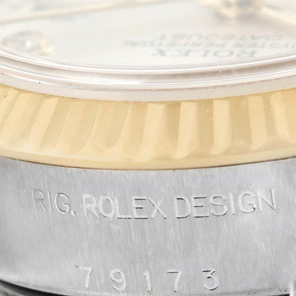 This close-up angle of the Rolex Datejust 79173 Women
s Stainless Steel Silver Dial 79173 Women
s Stainless Steel Silver Dial watch shows the bezel, part of the crystal, and the "ORIG. ROLEX DESIGN" engraving with the model number.