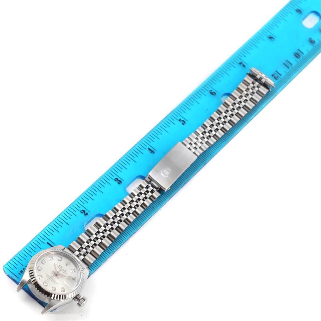 The image shows a Rolex Datejust 79174 Women
s Stainless Steel Silver Dial 79174 Women
s Stainless Steel Silver Dial watch laid flat next to a blue ruler, showcasing the dial, bezel, and bracelet.