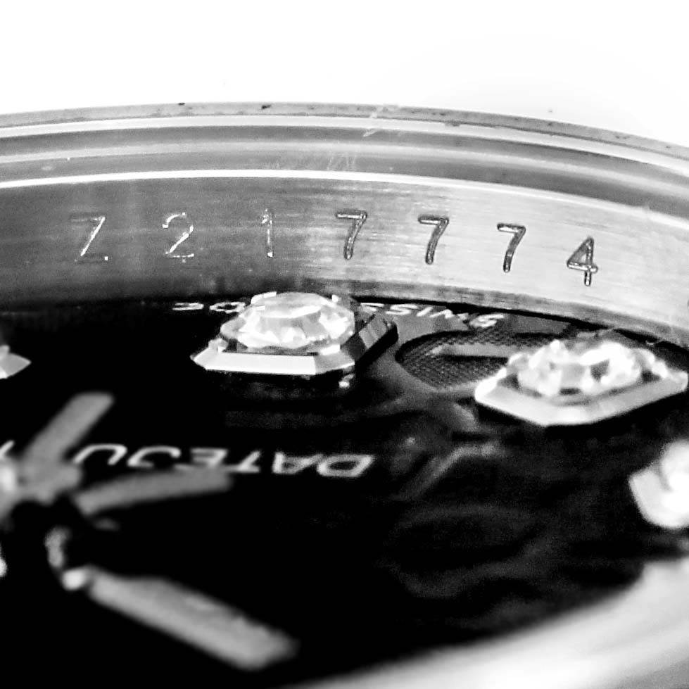 This close-up image of the Rolex Datejust 179174 Women's Stainless Steel Black Dial 179174 Women's Stainless Steel Black Dial watch shows the model's serial number on the inner bezel and part of the watch dial with diamond markers.