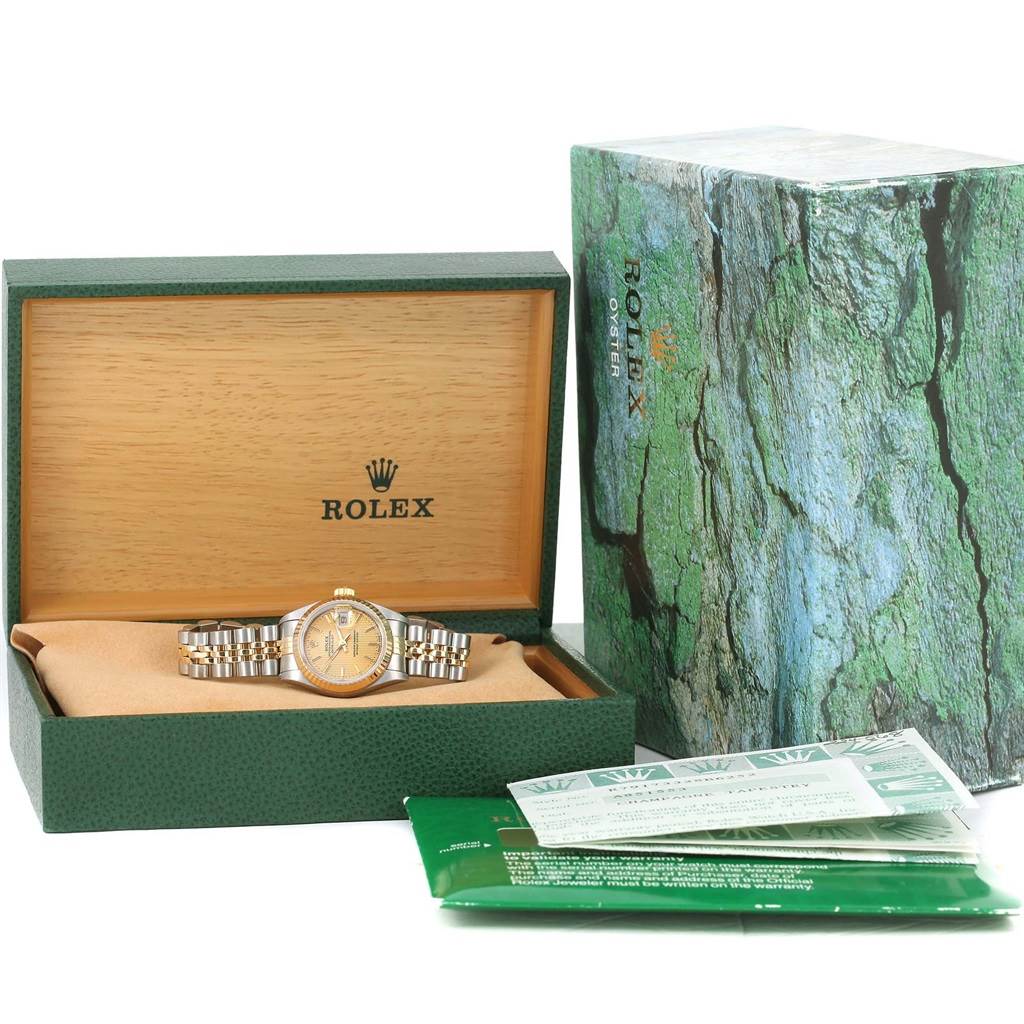 A Rolex Datejust 79173 Women
s Stainless Steel Champagne Dial 79173 Women
s Stainless Steel Champagne Dial watch is displayed in its open green box, with accompanying papers and an outer box beside it.