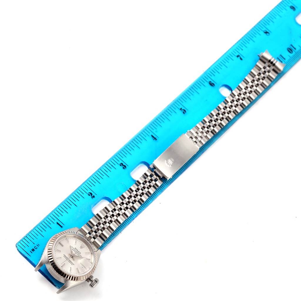 The Rolex Datejust 79174 Women's Stainless Steel Silver Dial 79174 Women's Stainless Steel Silver Dial watch is shown from above with its bracelet laid flat next to a blue ruler for scale.