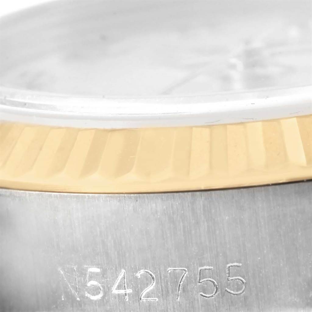 This image shows a close-up of the Rolex Datejust 69173 Women's Stainless Steel Beige Dial 69173 Women's Stainless Steel Beige Dial watch’s bezel and serial number engraving at an angle.