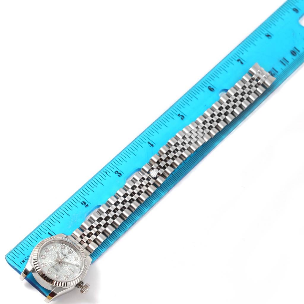 The Rolex Datejust 179174 Women's Stainless Steel Blue Dial 179174 Women's Stainless Steel Blue Dial watch is shown flat next to a blue ruler, displaying the entire bracelet and watch face.