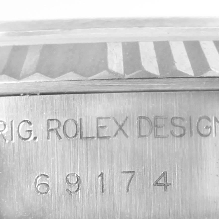 The image shows a close-up of the engraved case of the Rolex Datejust 69174 Women
s Stainless Steel Pink Dial 69174 Women
s Stainless Steel Pink Dial model, focusing on the serial number and design text.