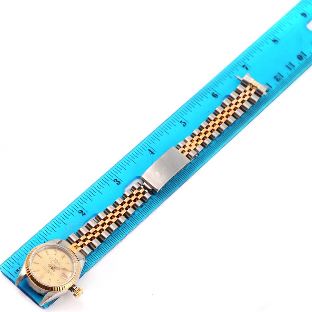 The image shows a Rolex Datejust 69173 Women's Stainless Steel Champagne Dial 69173 Women's Stainless Steel Champagne Dial watch with a jubilee bracelet next to a blue ruler, displaying its full length.