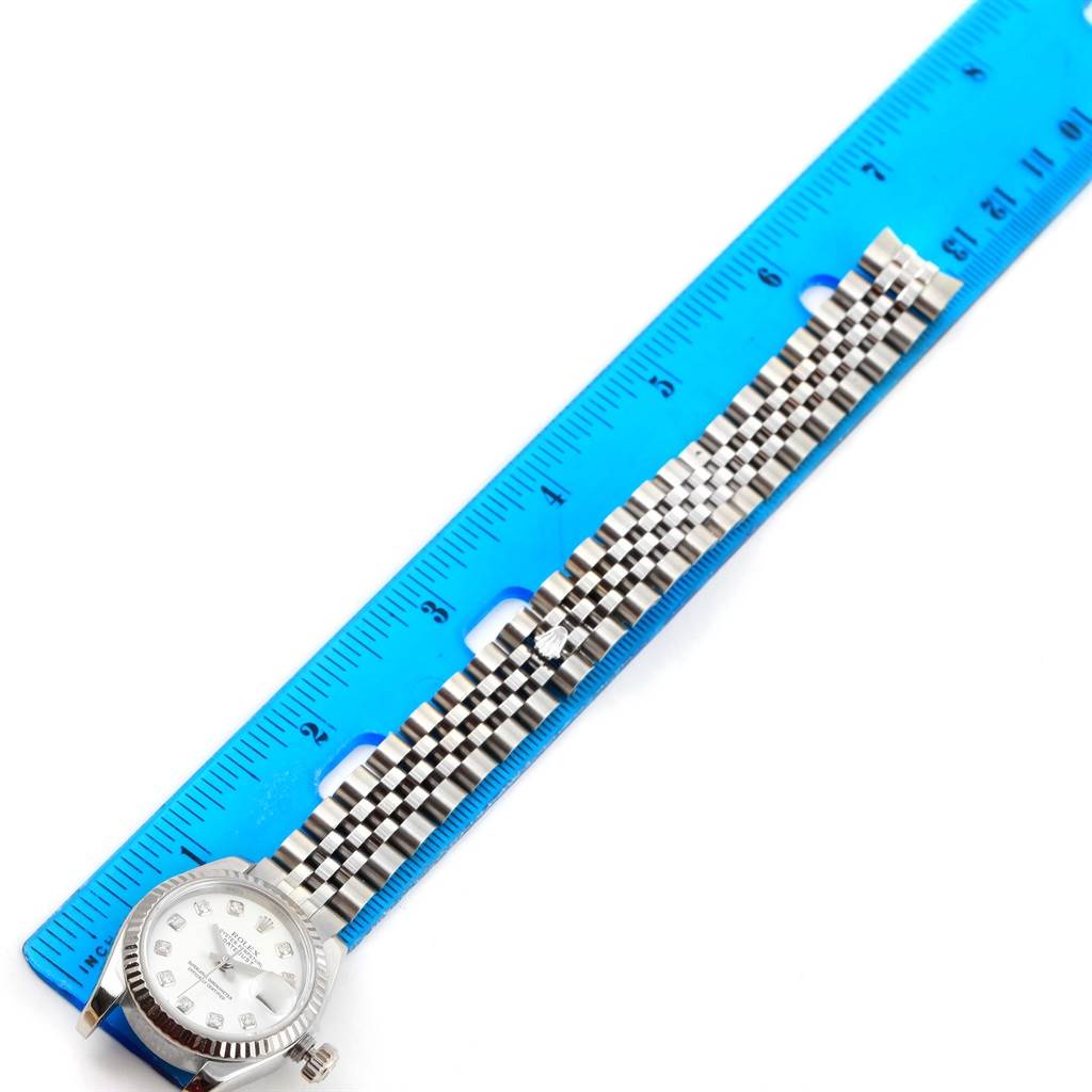 The image shows a Rolex Datejust 179174 Women
s Stainless Steel White Dial 179174 Women
s Stainless Steel White Dial watch laid next to a blue ruler, displaying the face and full length of the band.