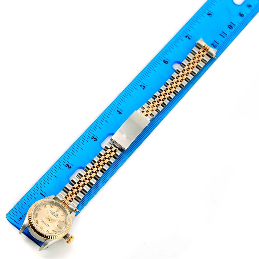 This image shows a Rolex Datejust 69173 Women
s Stainless Steel Champagne Dial 69173 Women
s Stainless Steel Champagne Dial watch laid flat beside a blue ruler, displaying the dial and entire band.