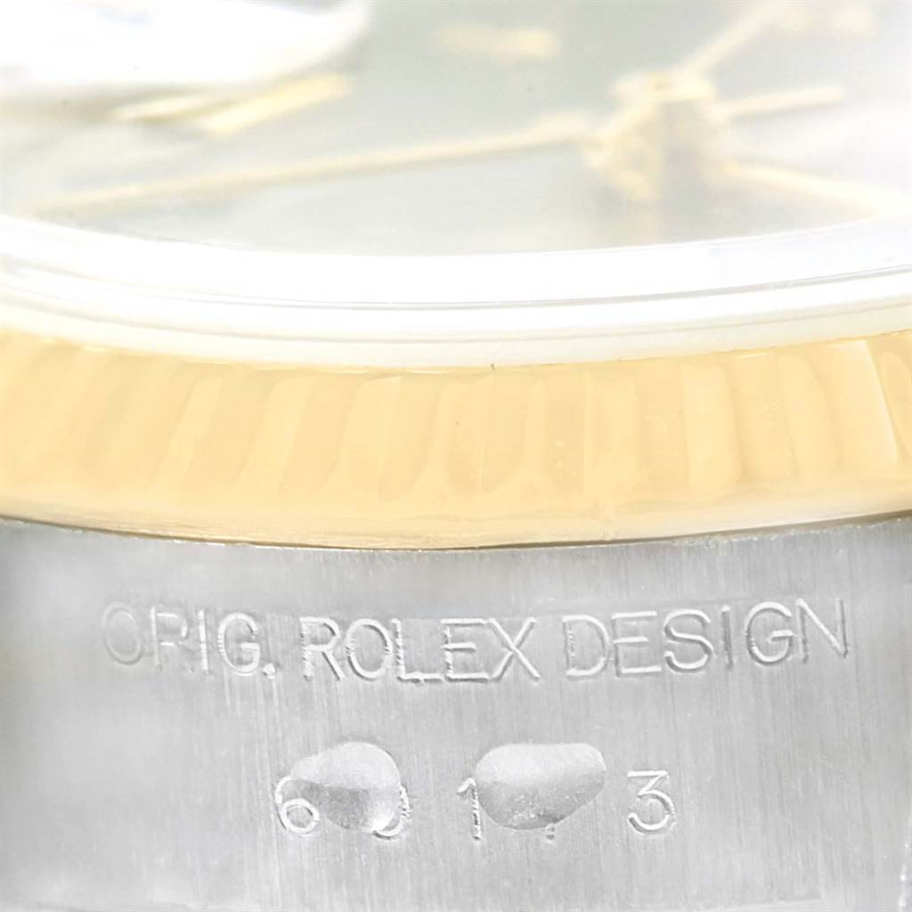 This close-up image of the Rolex Datejust 69173 Women
s Stainless Steel Grey Dial 69173 Women
s Stainless Steel Grey Dial model focuses on the bezel and engraved "ORIG. ROLEX DESIGN" text on the case.