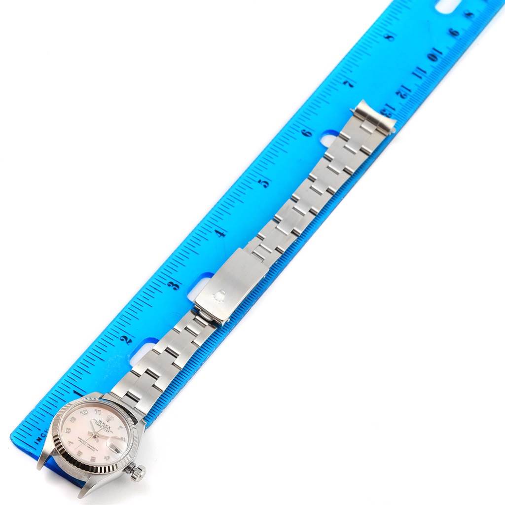 The image shows a Rolex Datejust 79174 Women's Stainless Steel Mother of Pearl Dial 79174 Women's Stainless Steel Mother of Pearl Dial watch positioned alongside a blue ruler, highlighting its bracelet and clasp.