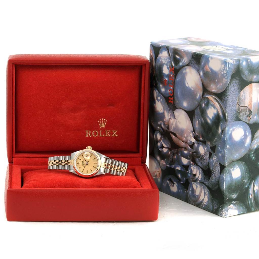 The Rolex Datejust 69173 Women
s Stainless Steel Champagne Dial 69173 Women
s Stainless Steel Champagne Dial watch is displayed frontally in a red box with its bracelet fully visible and a patterned outer box beside it.