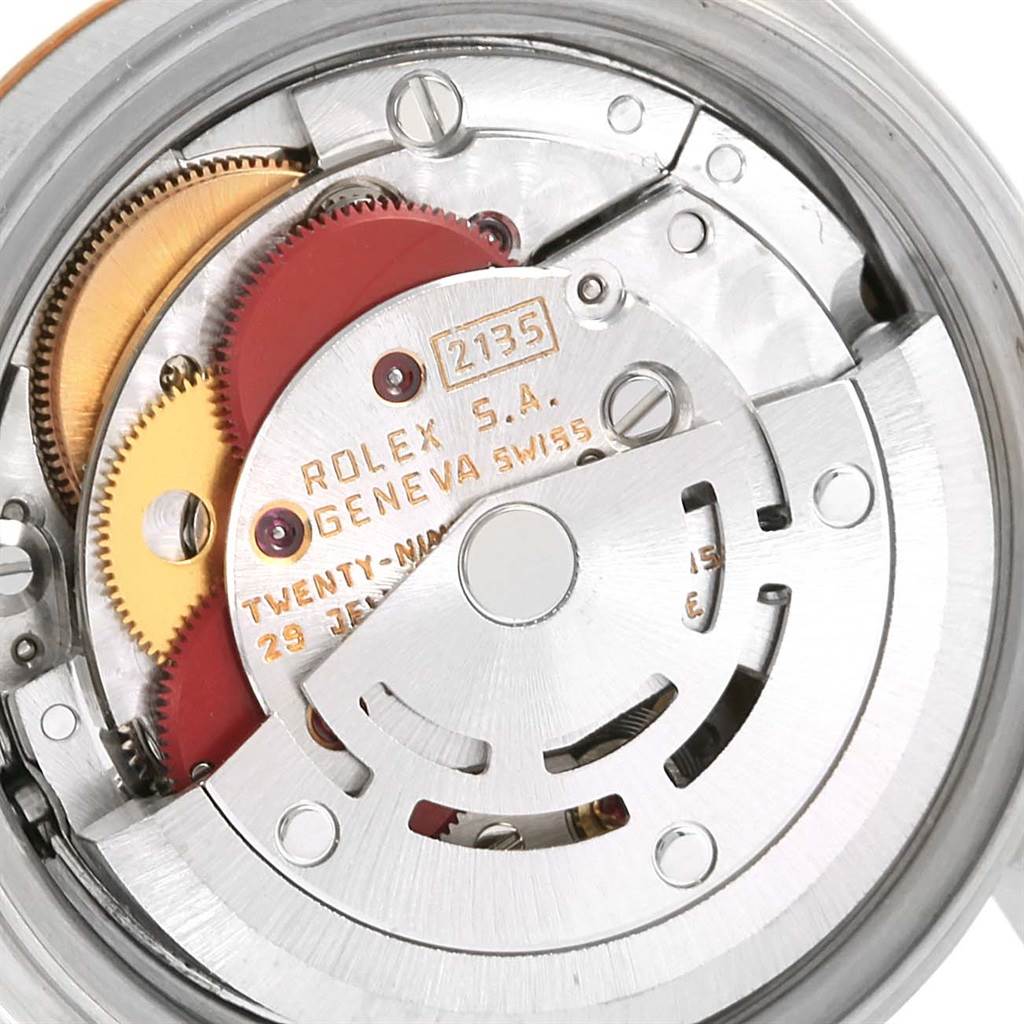 The image shows a close-up of the movement mechanism of a Rolex Datejust 69173 Women
s Stainless Steel Champagne Dial 69173 Women
s Stainless Steel Champagne Dial watch, highlighting gears and engraved details.