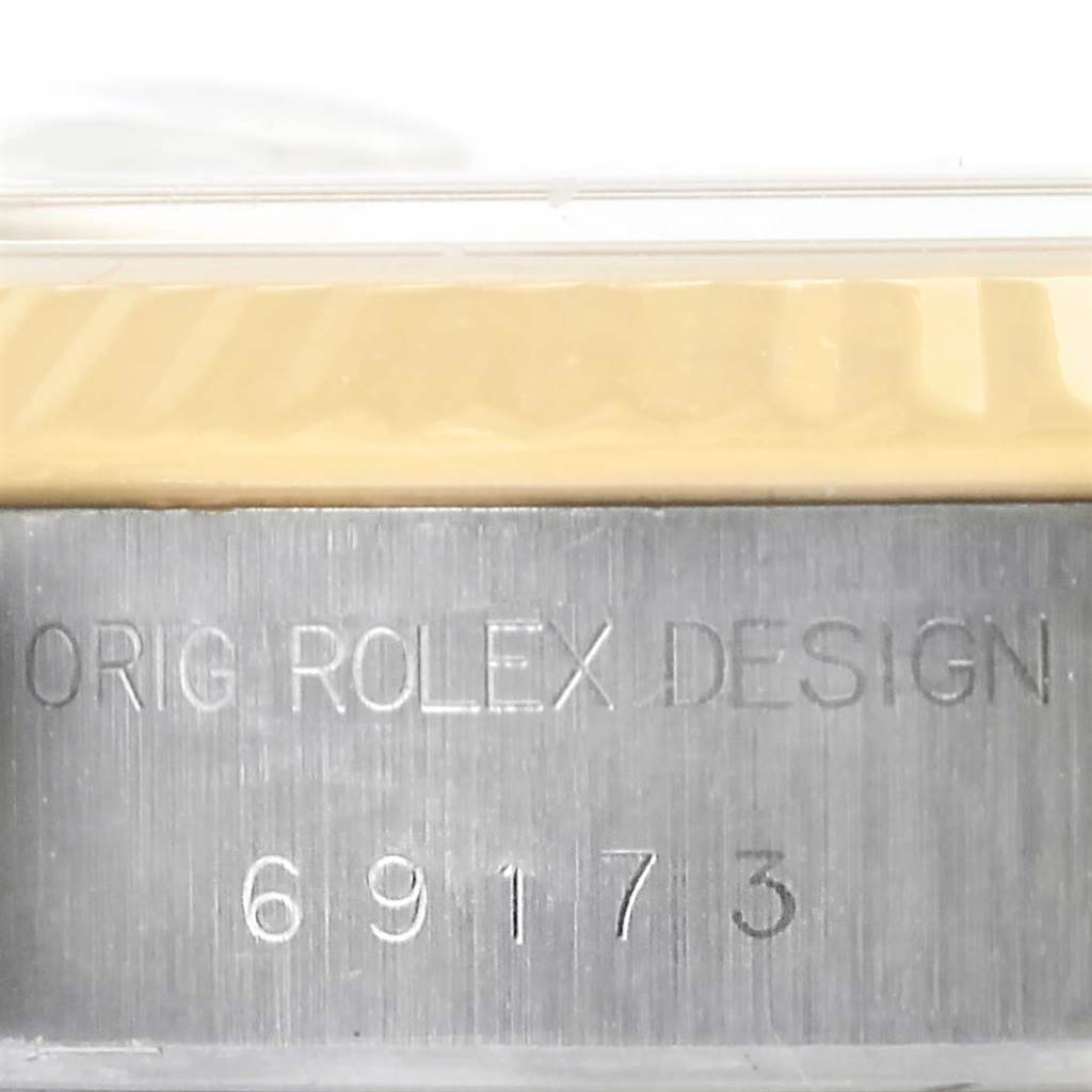 The image shows a close-up of the case side of a Rolex Datejust 69173 Women
s Stainless Steel Black Dial 69173 Women
s Stainless Steel Black Dial watch, displaying the engraving "ORIG ROLEX DESIGN 69173."