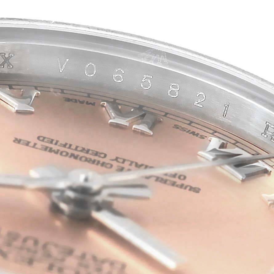 This close-up angle of the Rolex Datejust 179174 Women's Stainless Steel Pink Dial 179174 Women's Stainless Steel Pink Dial watch shows part of the dial, Roman numeral indices, hands, and part of the inner bezel with a serial number.