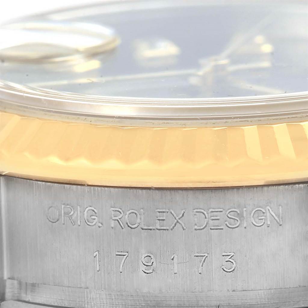 This is a close-up angled shot of a Rolex Datejust 179173 Women's Steel and Gold (two tone) Black Dial 179173 Women's Steel and Gold (two tone) Black Dial, focused on the bezel and case with engraving.