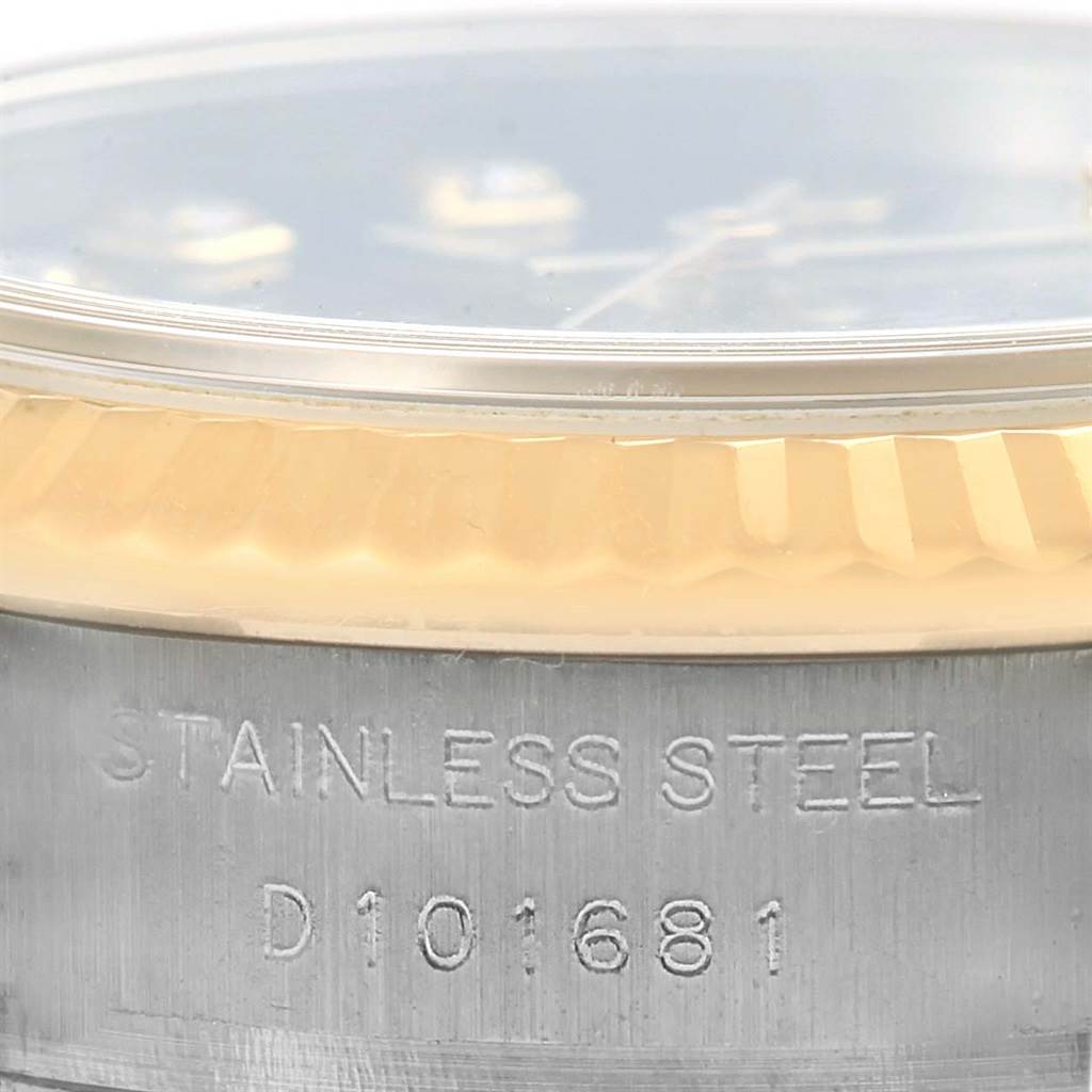 This image shows a close-up of the Rolex Datejust 179173 Women's Steel and Gold (two tone) Black Dial 179173 Women's Steel and Gold (two tone) Black Dial's fluted bezel and stainless-steel case with engraved serial number.